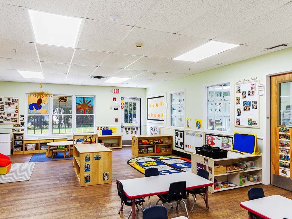 Empty classroom with small tables and chairs, shelves, and decorations on the walls