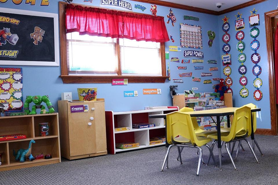 Classroom with small yellow chairs and table, shelves, and decorated walls