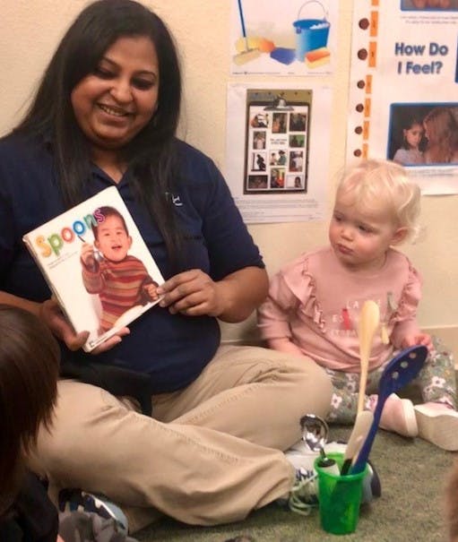 Person holding a book with a child on the cover, child sitting nearby
