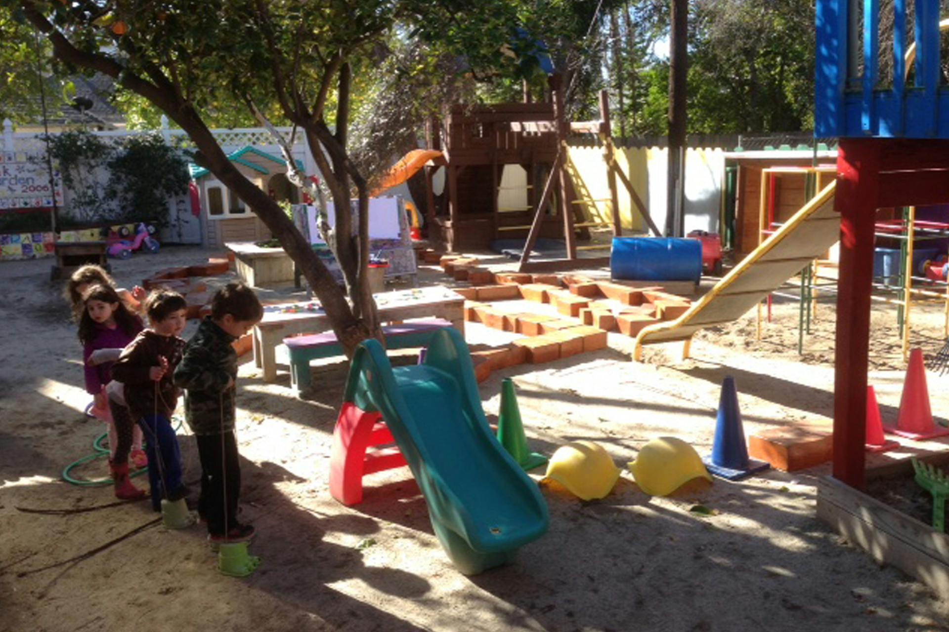 Children standing on a playground with slides and play structures