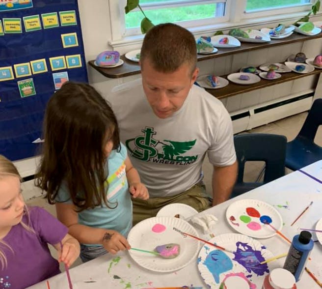 Adult and two children painting at a table