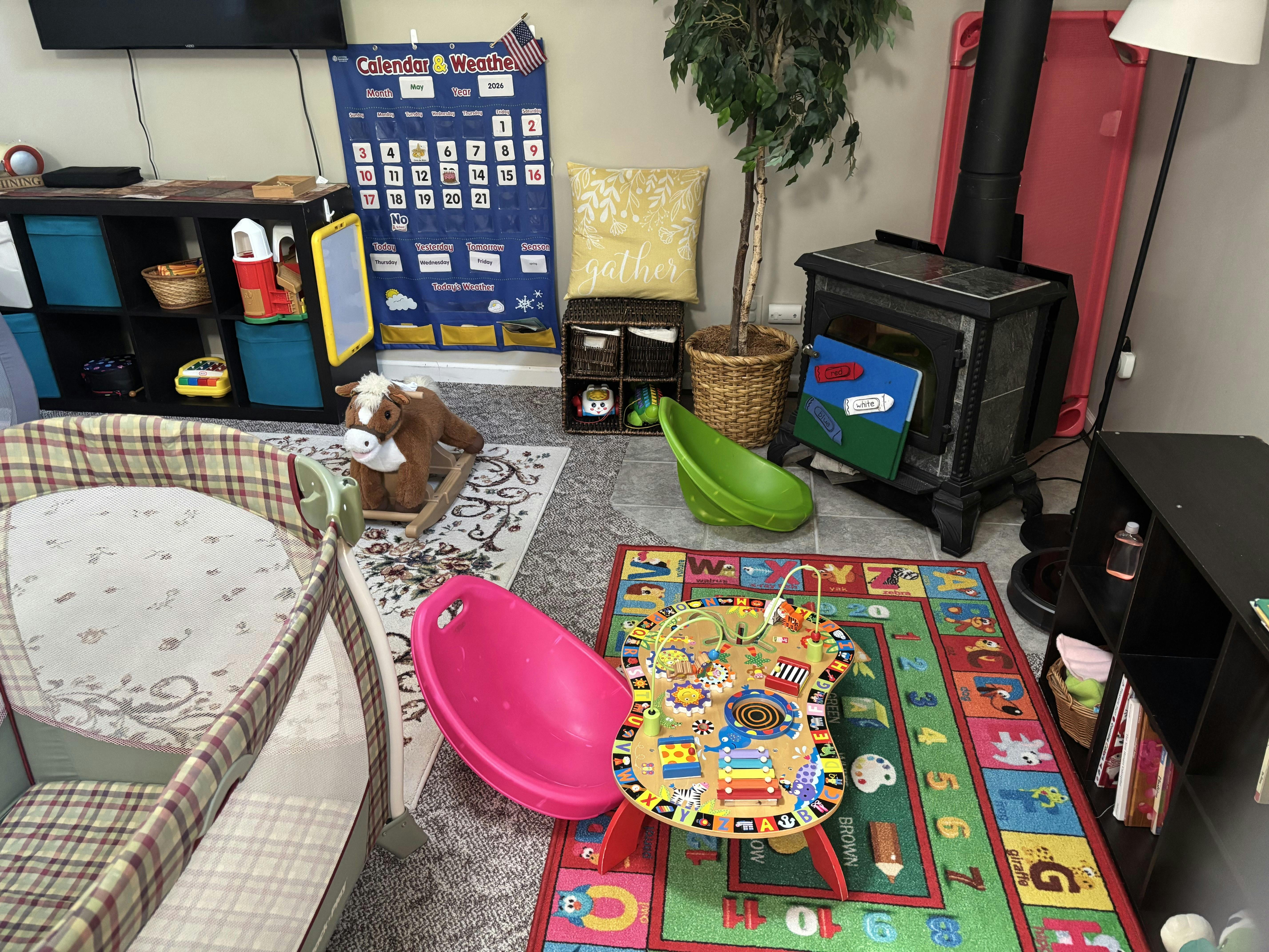 Playroom with a playpen, activity table, rocking toy, and calendar chart