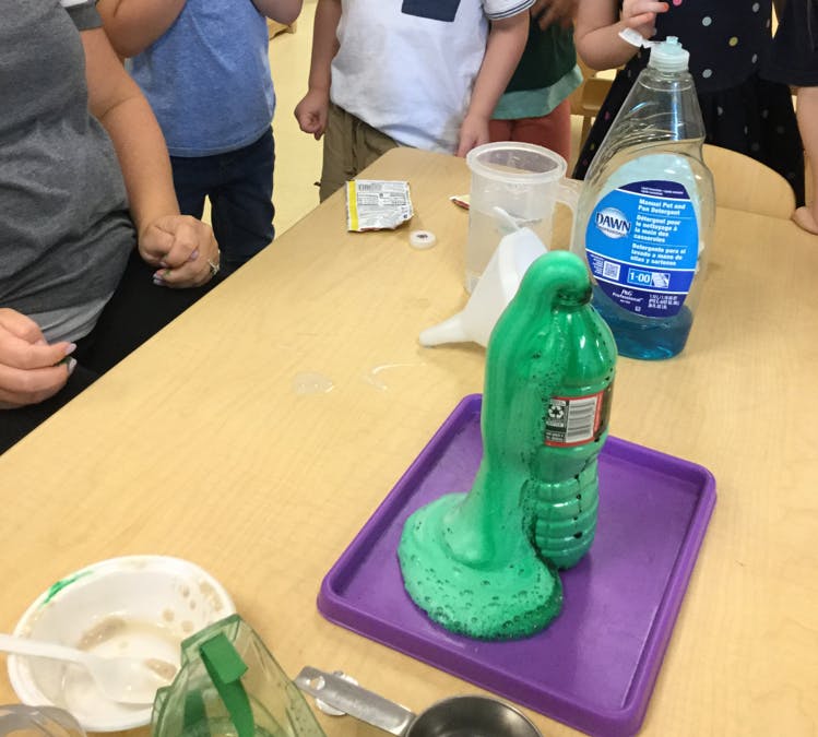 Green foam erupting from a bottle on a purple tray