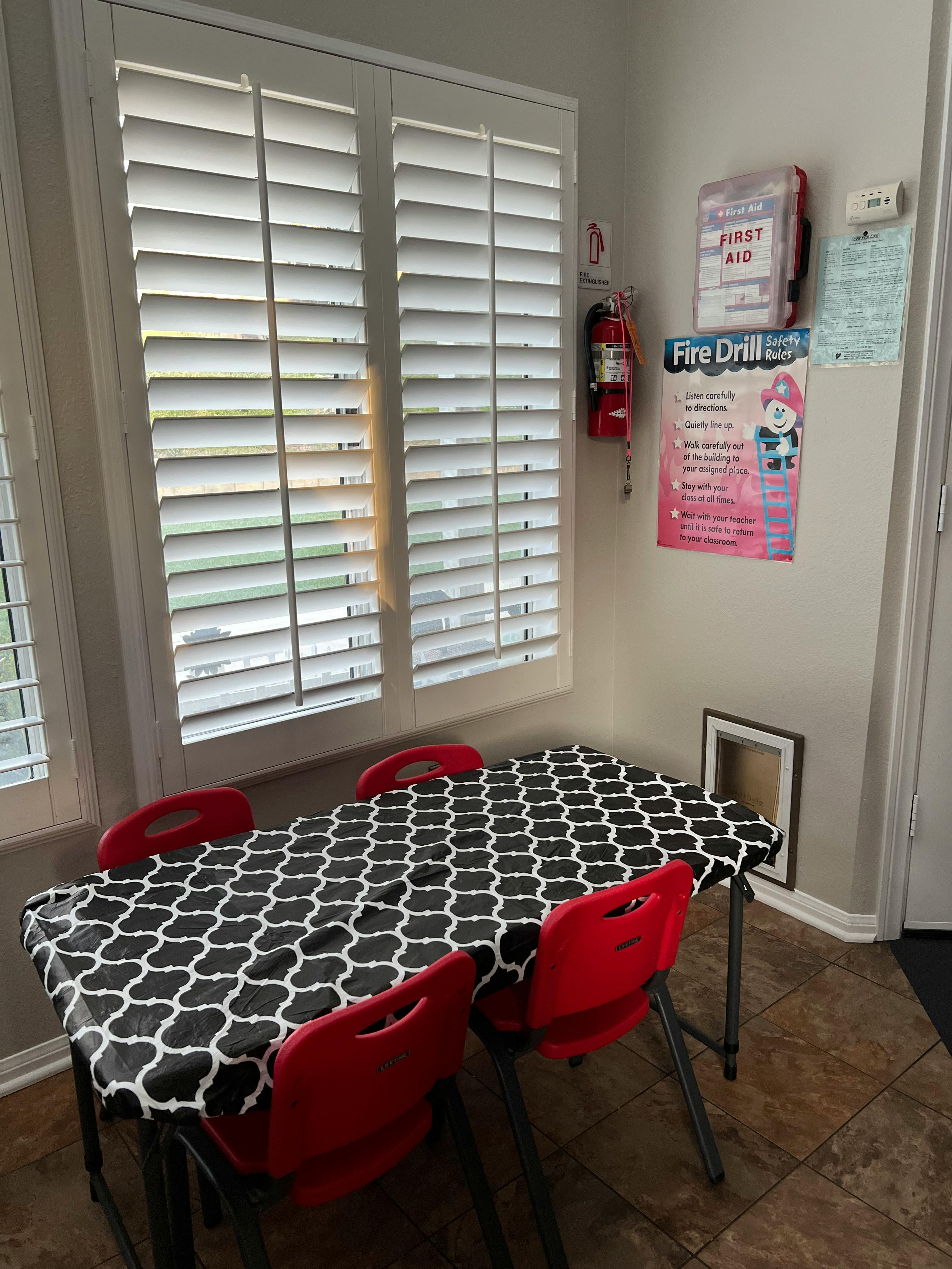 Table with black and white patterned tablecloth and red chairs