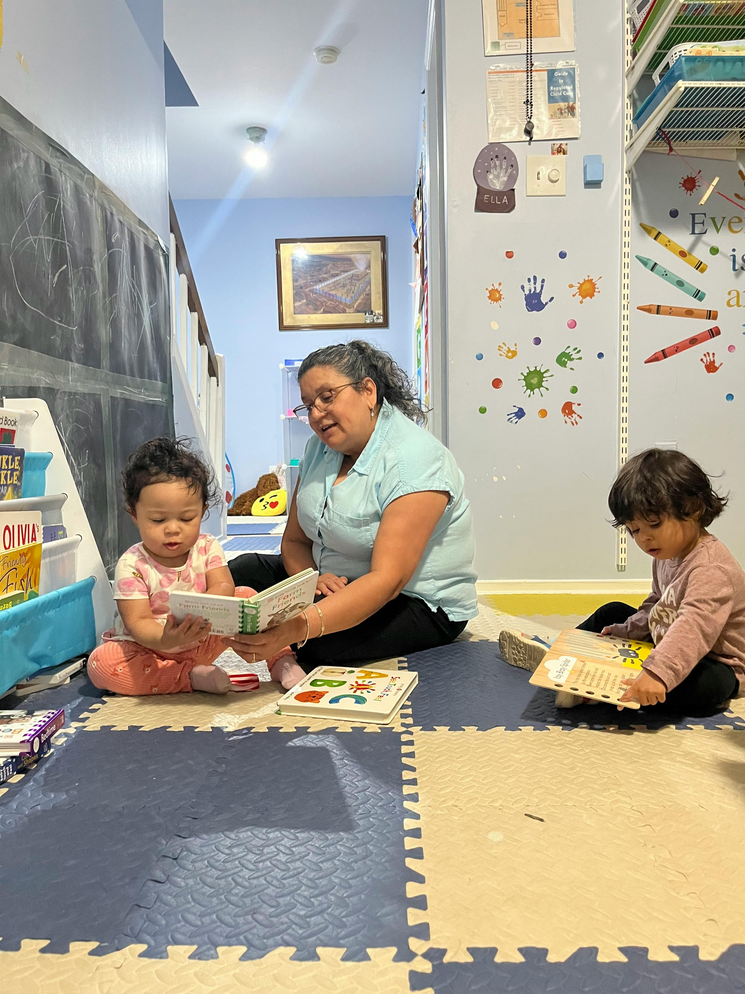 adult and two children sitting on a mat looking at books