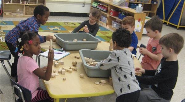 Children playing with blocks at a table in a classroom