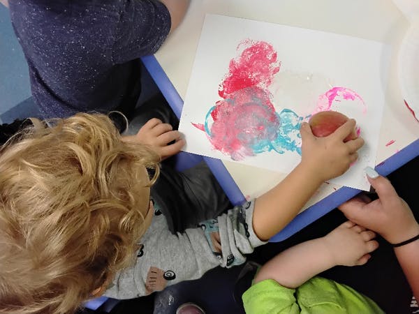 Child using a sponge to paint on paper