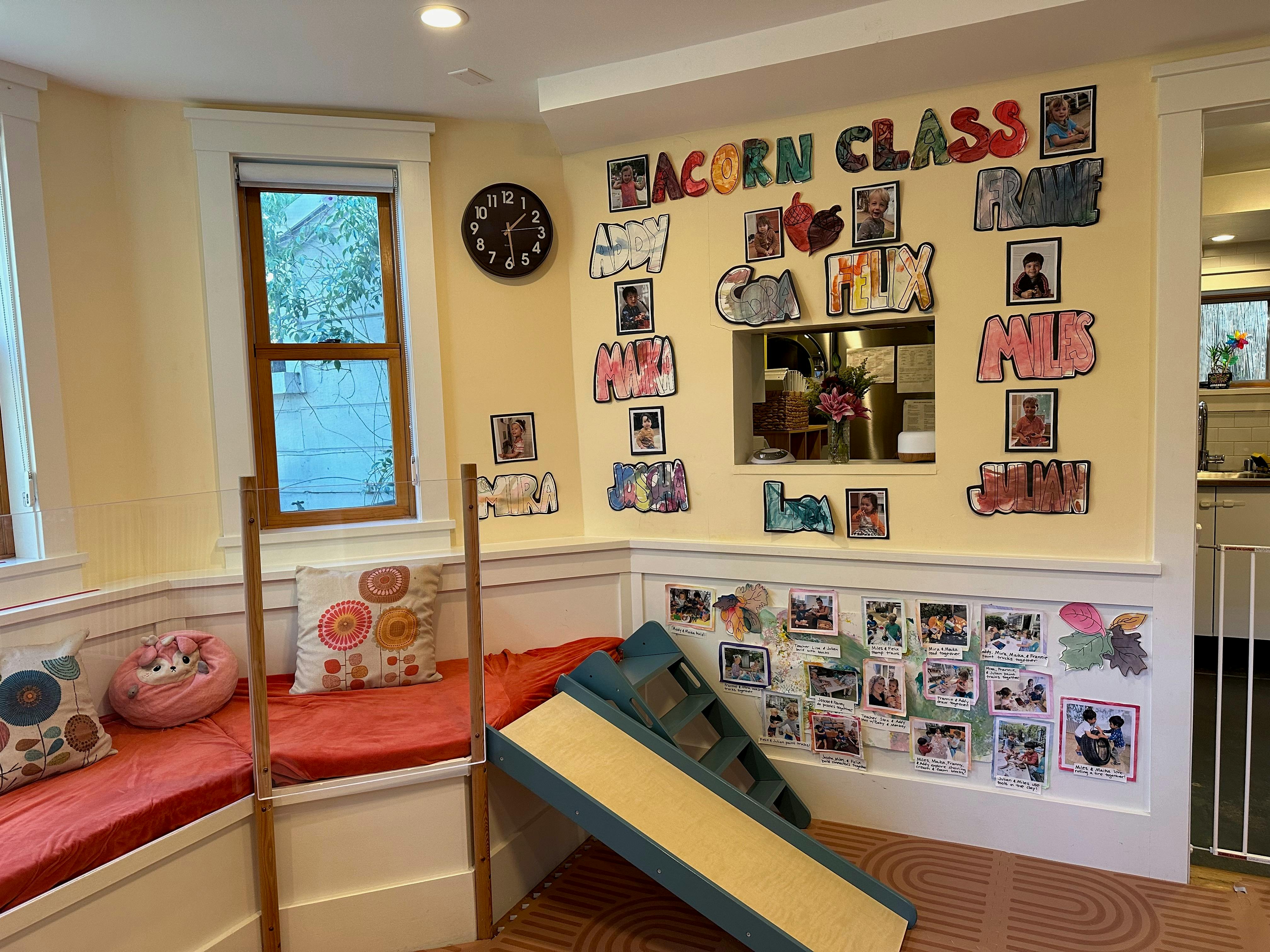 Children's classroom with window seating, a small slide, and artwork on the walls