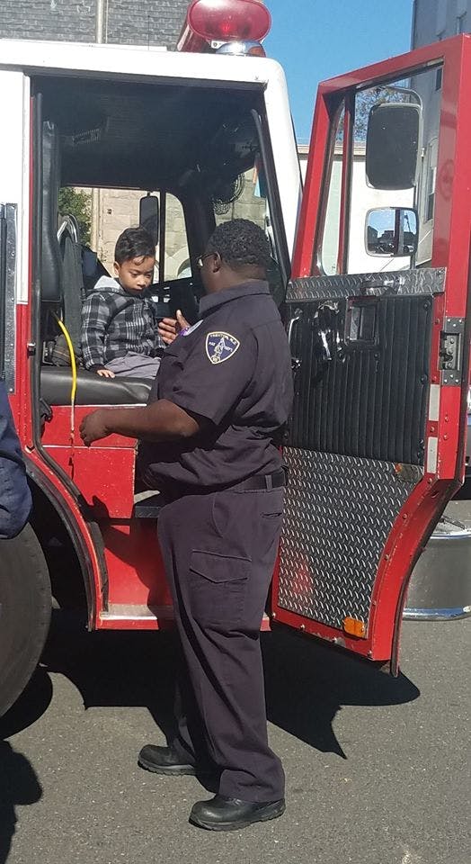 Person in uniform talking to a child sitting in a fire truck