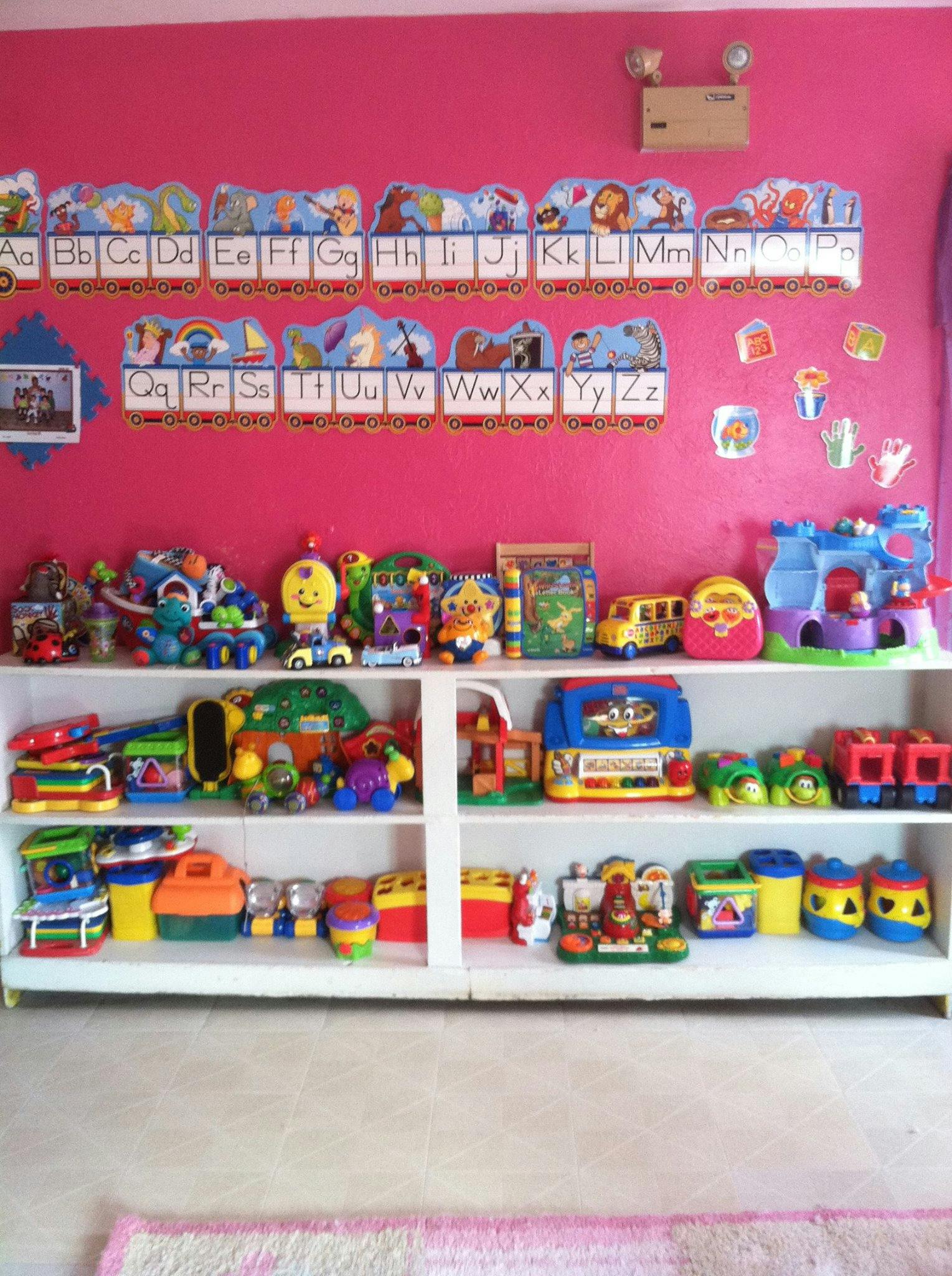Shelves filled with colorful children's toys and alphabet decorations on a pink wall