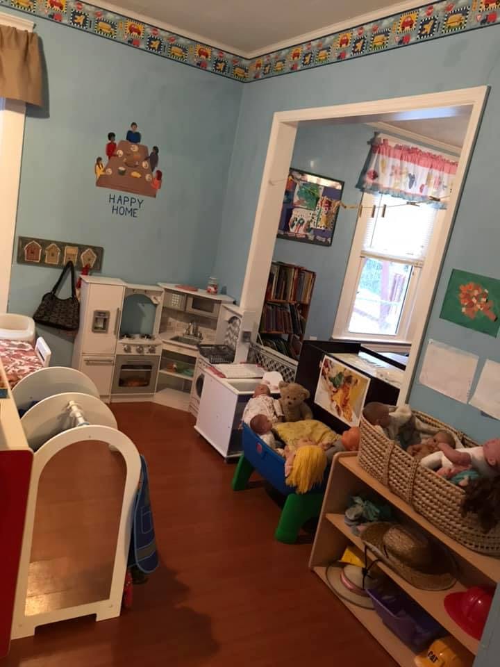 Playroom with toy kitchen, doll bed, and shelves of toys