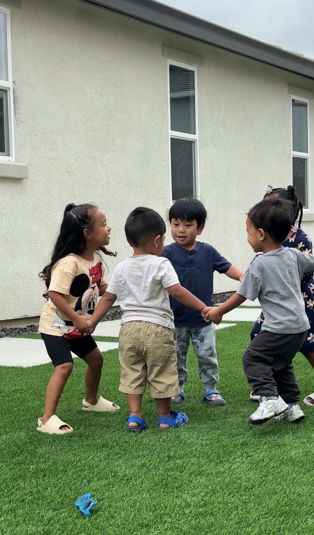 Children holding hands in a circle on artificial grass