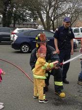 Firefighter helping child hold a fire hose