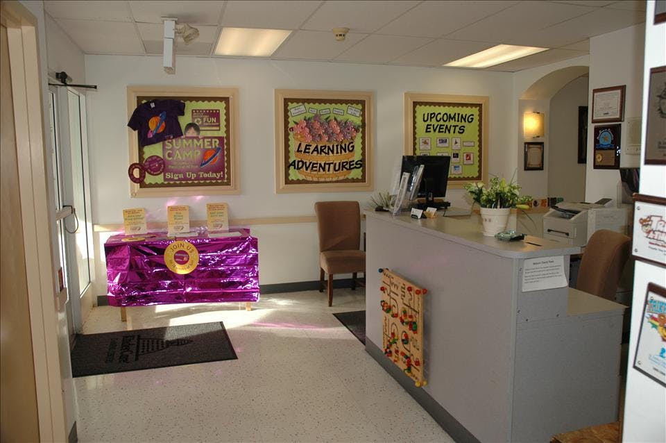 An empty reception area with a desk, chairs, and several bulletin boards