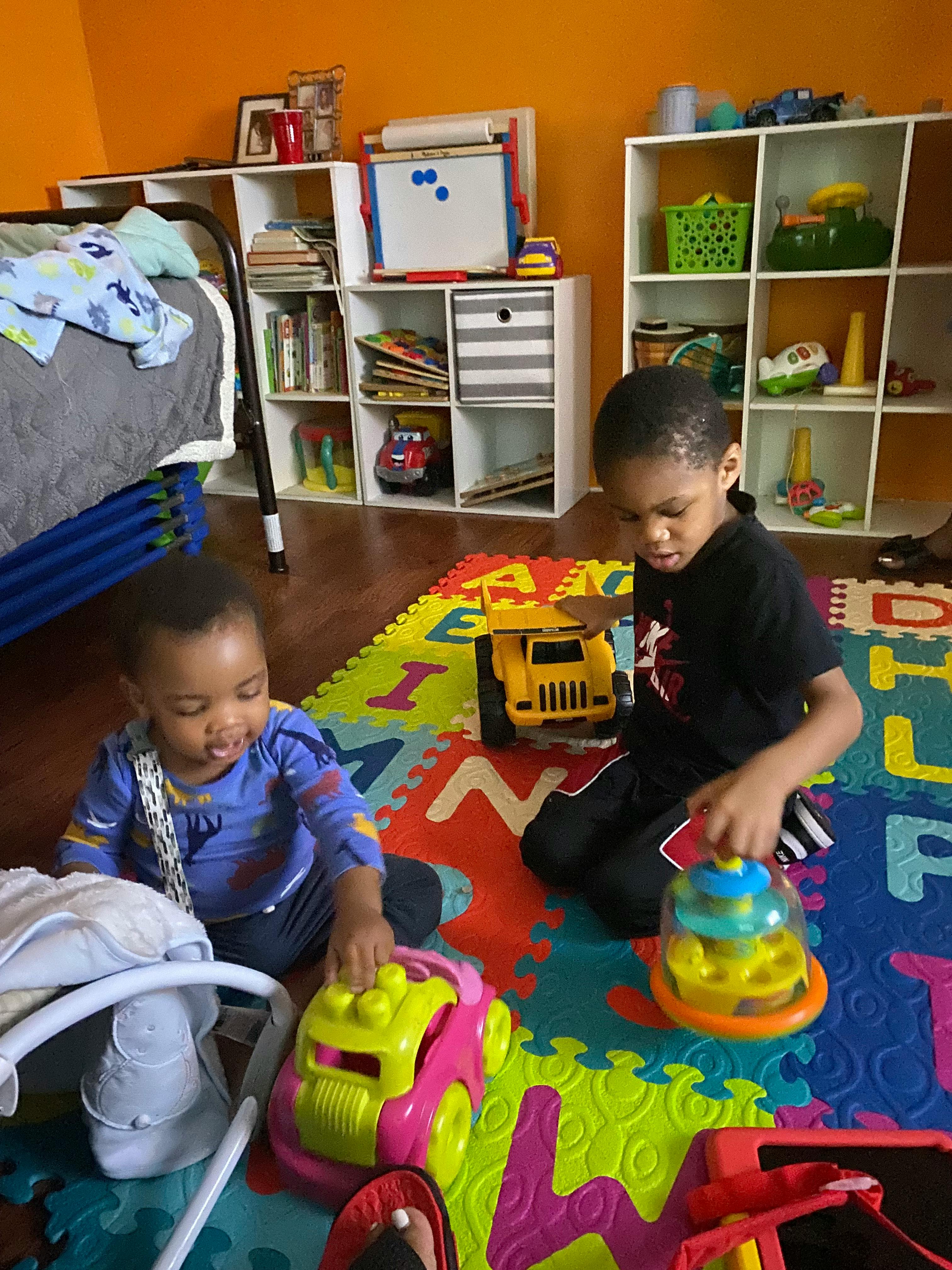 Two children playing with toys on a colorful mat