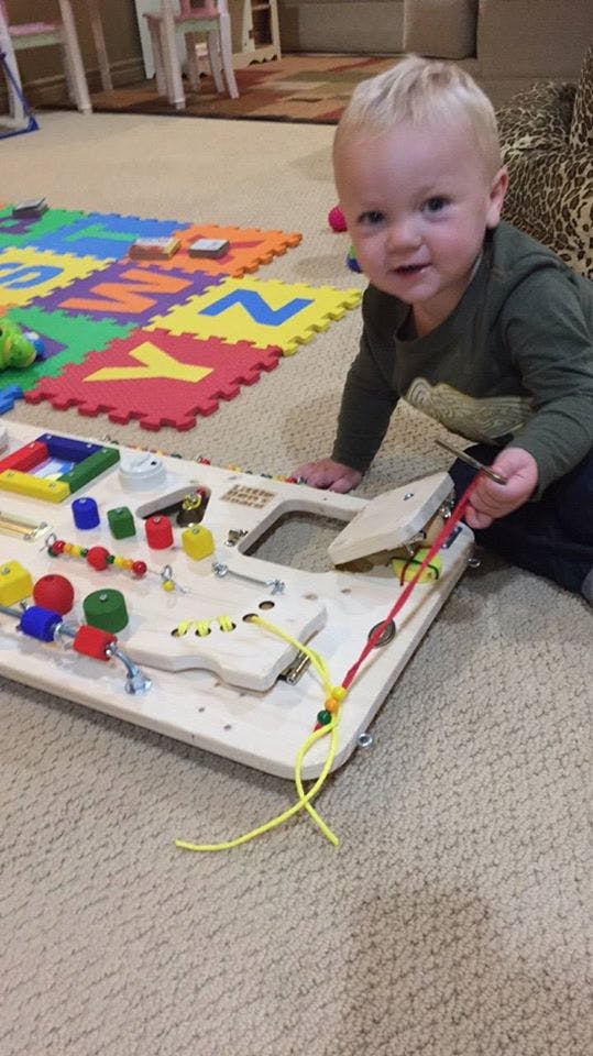 Child playing with a busy board on the floor