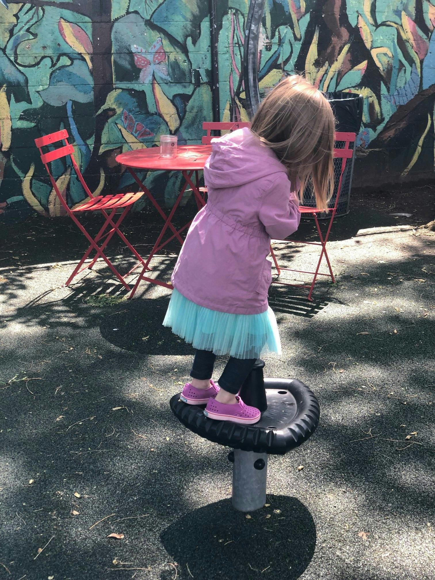 Child standing on a playground spinner