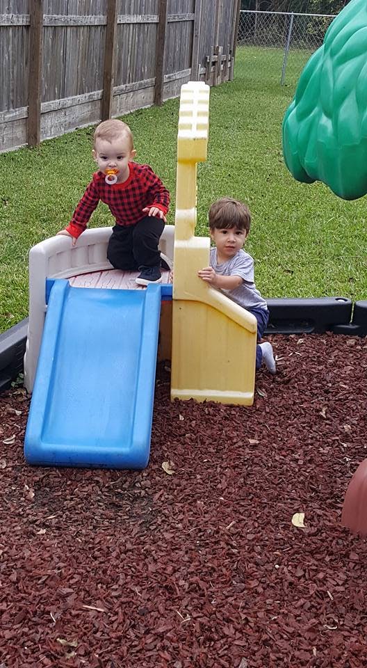 Two children playing on a small slide and climbing structure