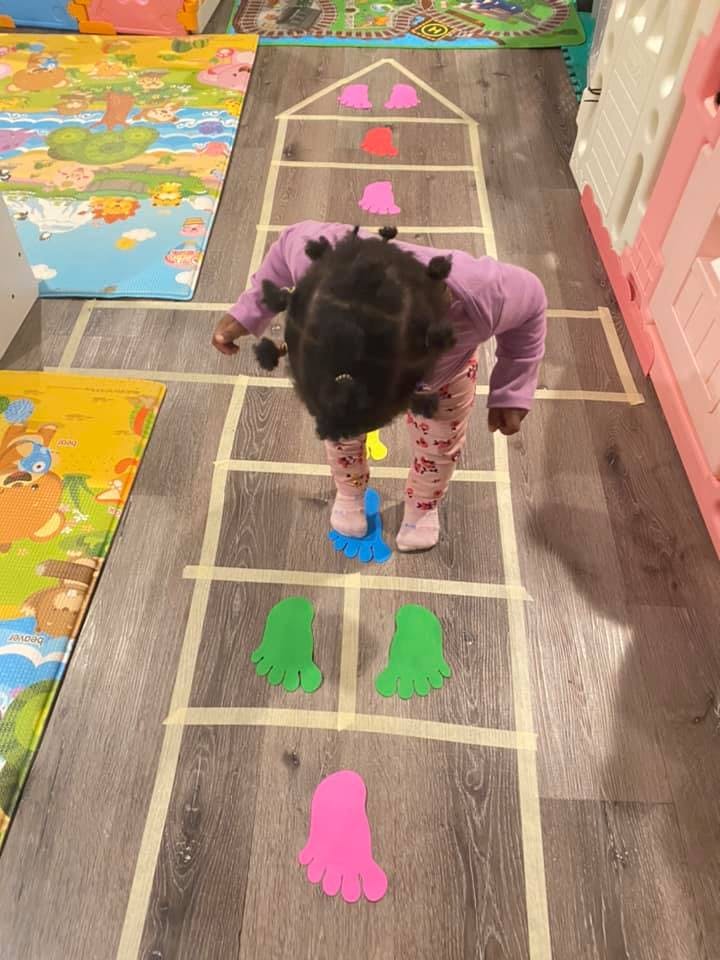 Child playing on a hopscotch grid with colorful foot cutouts