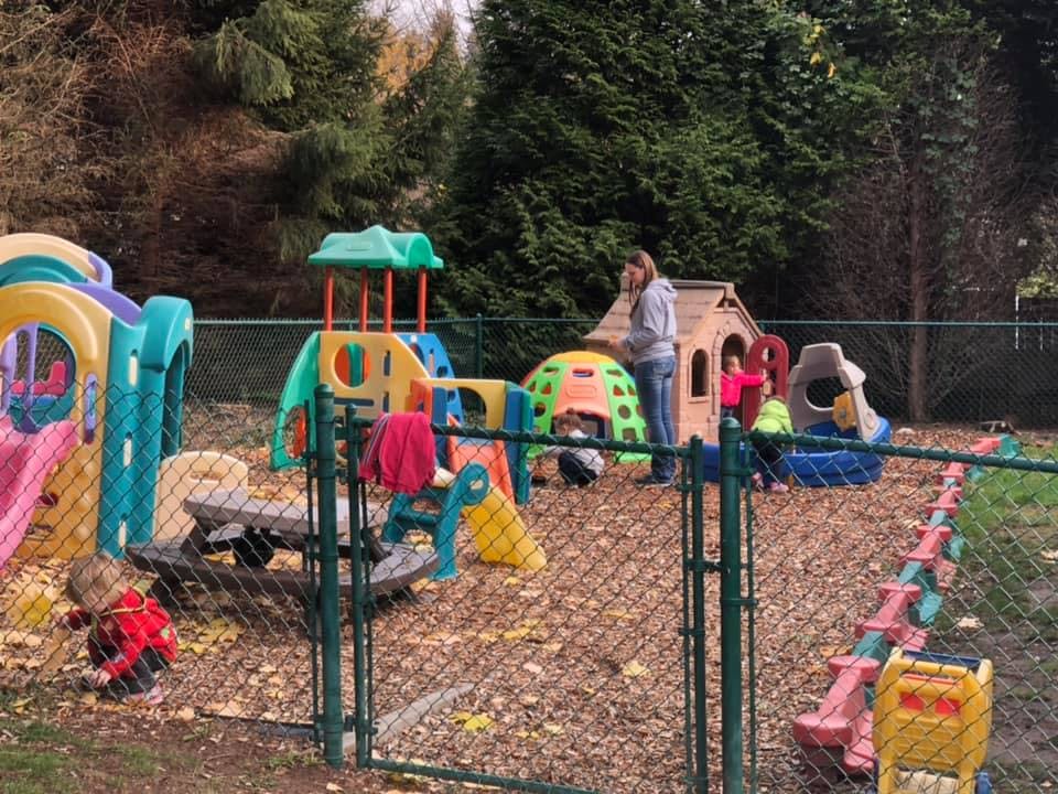 Adult and children on a playground with play structures