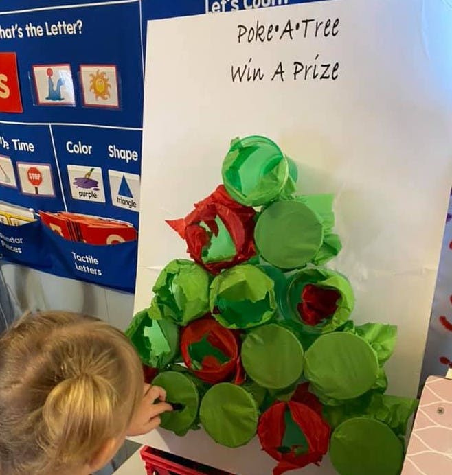 Child playing a "Poke A Tree" game with green and red cups