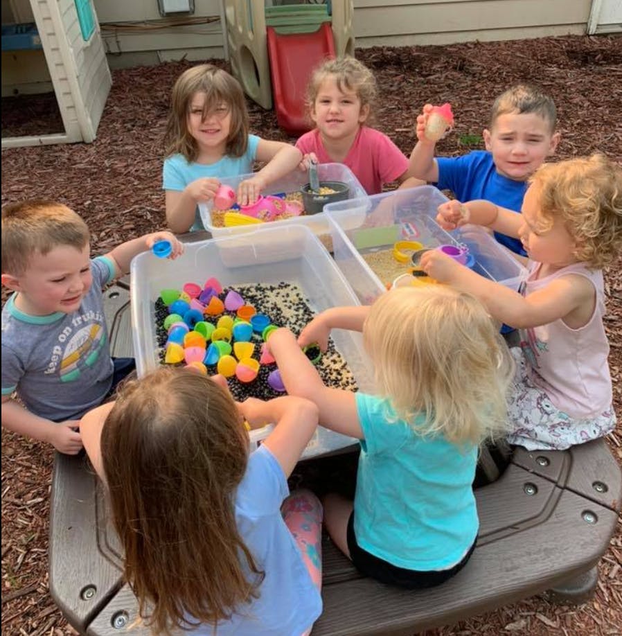 Children playing with sensory bins outdoors