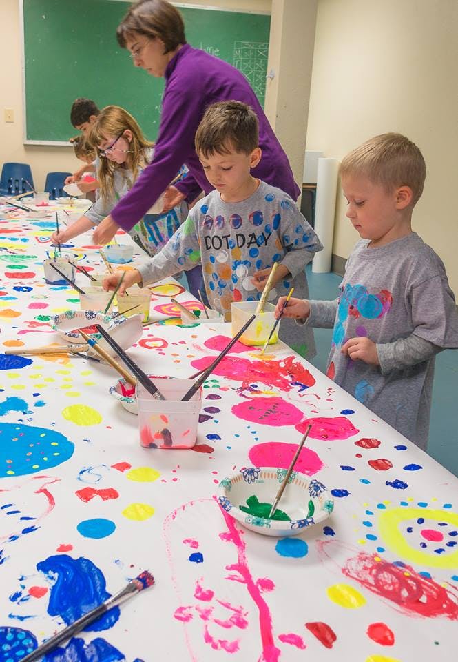 Adult and children painting at a long table