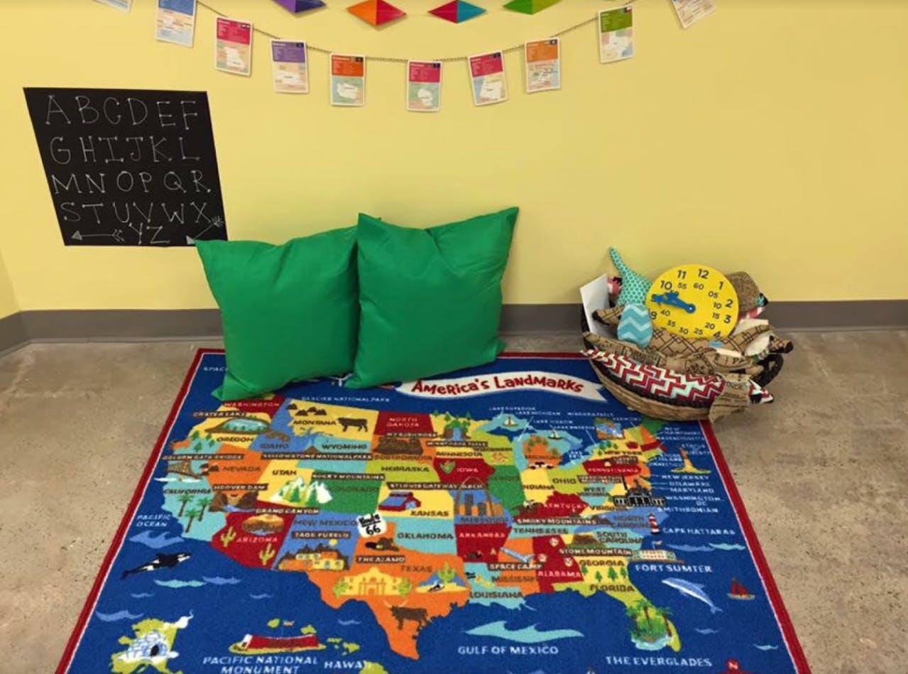 Map of the United States on a rug with green pillows and a basket of toys