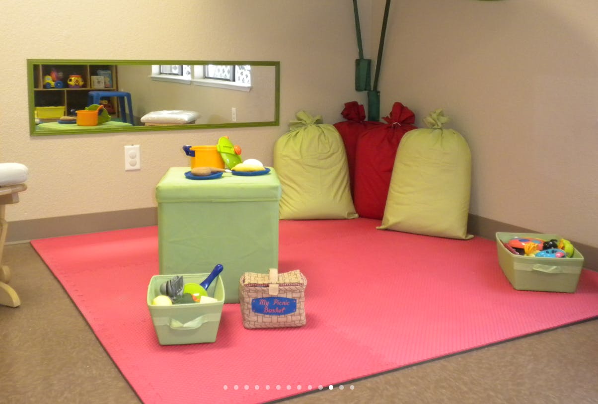 Playroom with a pink mat, green ottoman, and toy bins