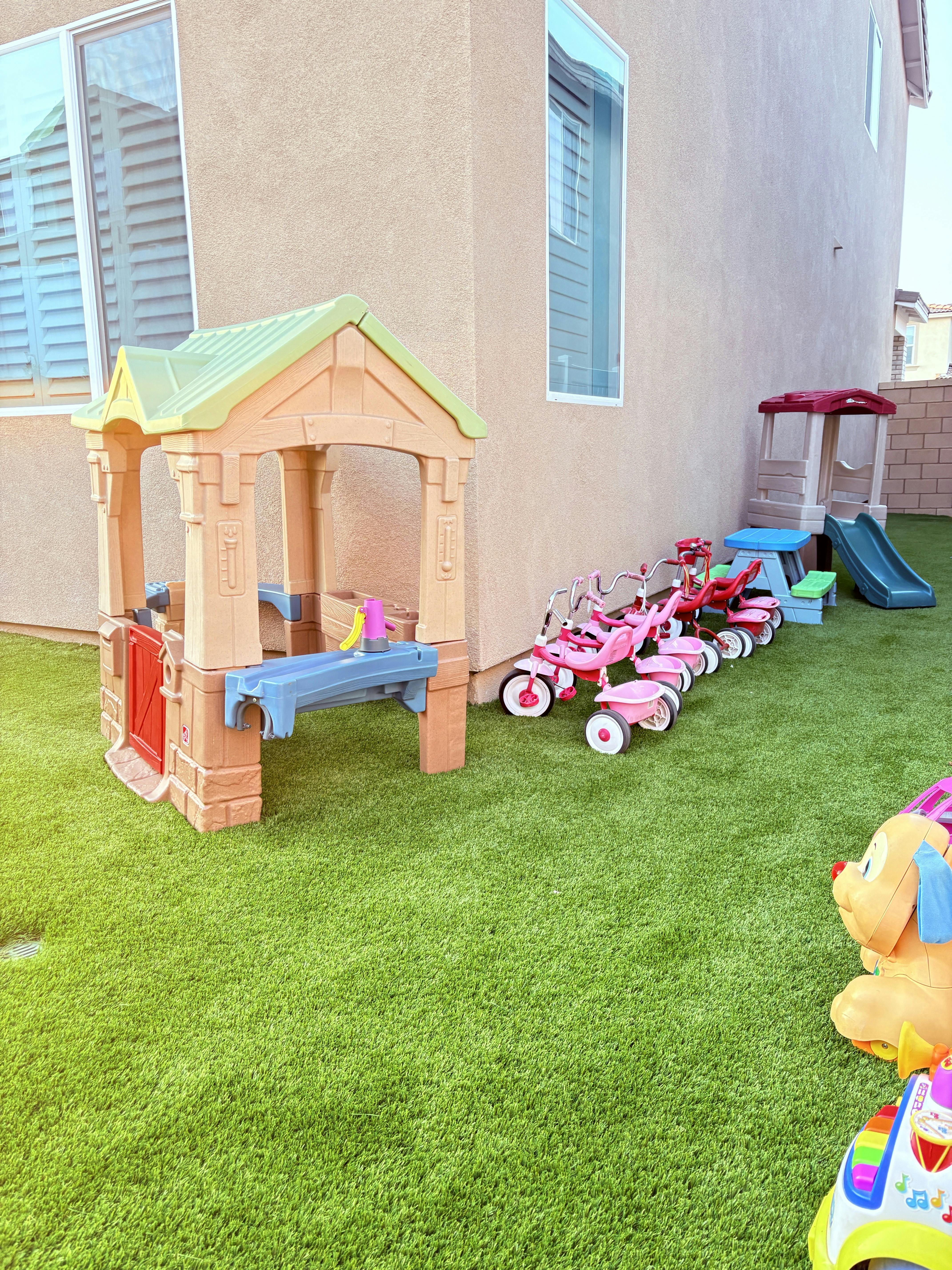 Playhouse and tricycles on artificial grass