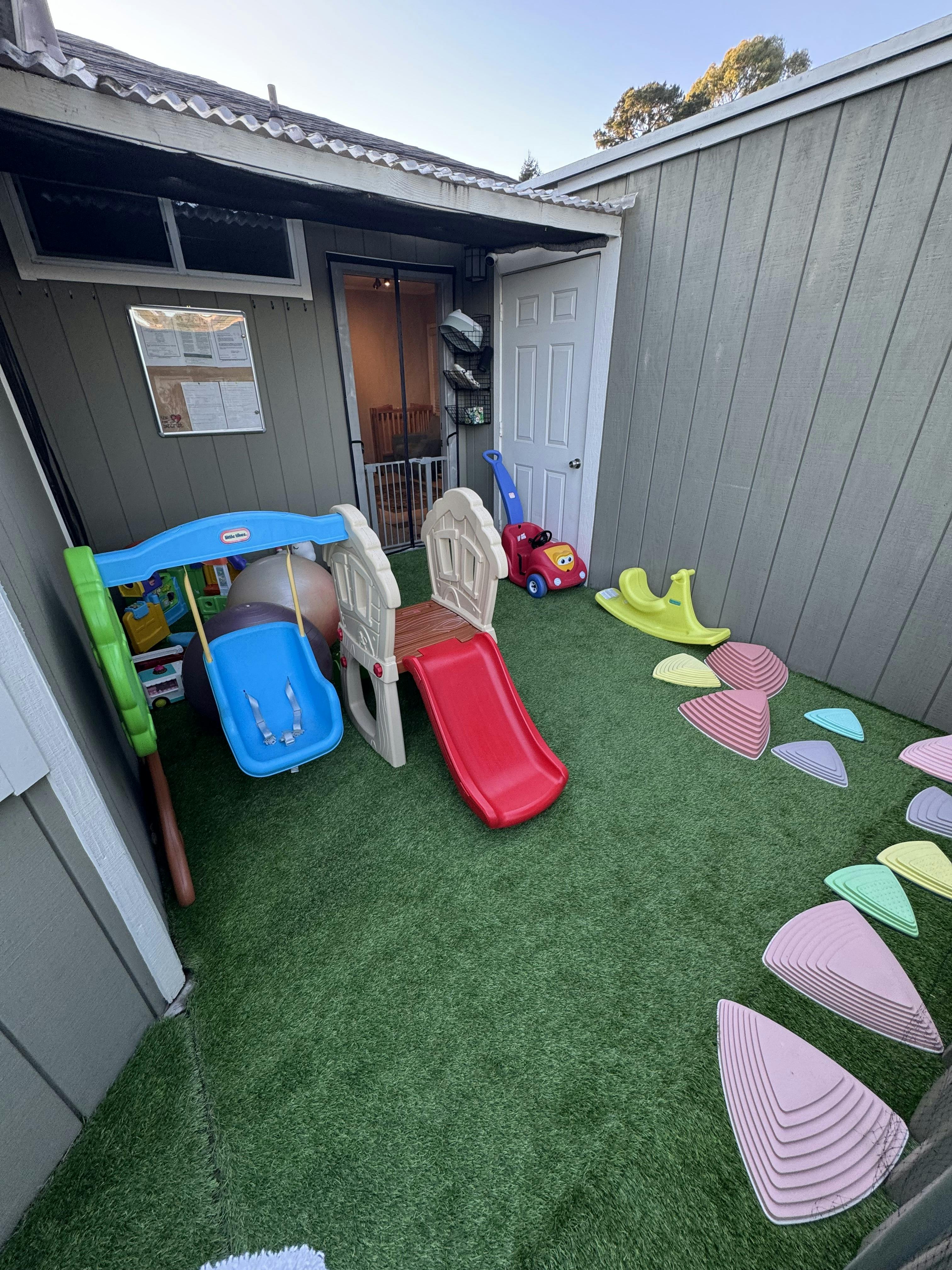 Children's playground with slides, swing, ride-on toys, and stepping stones