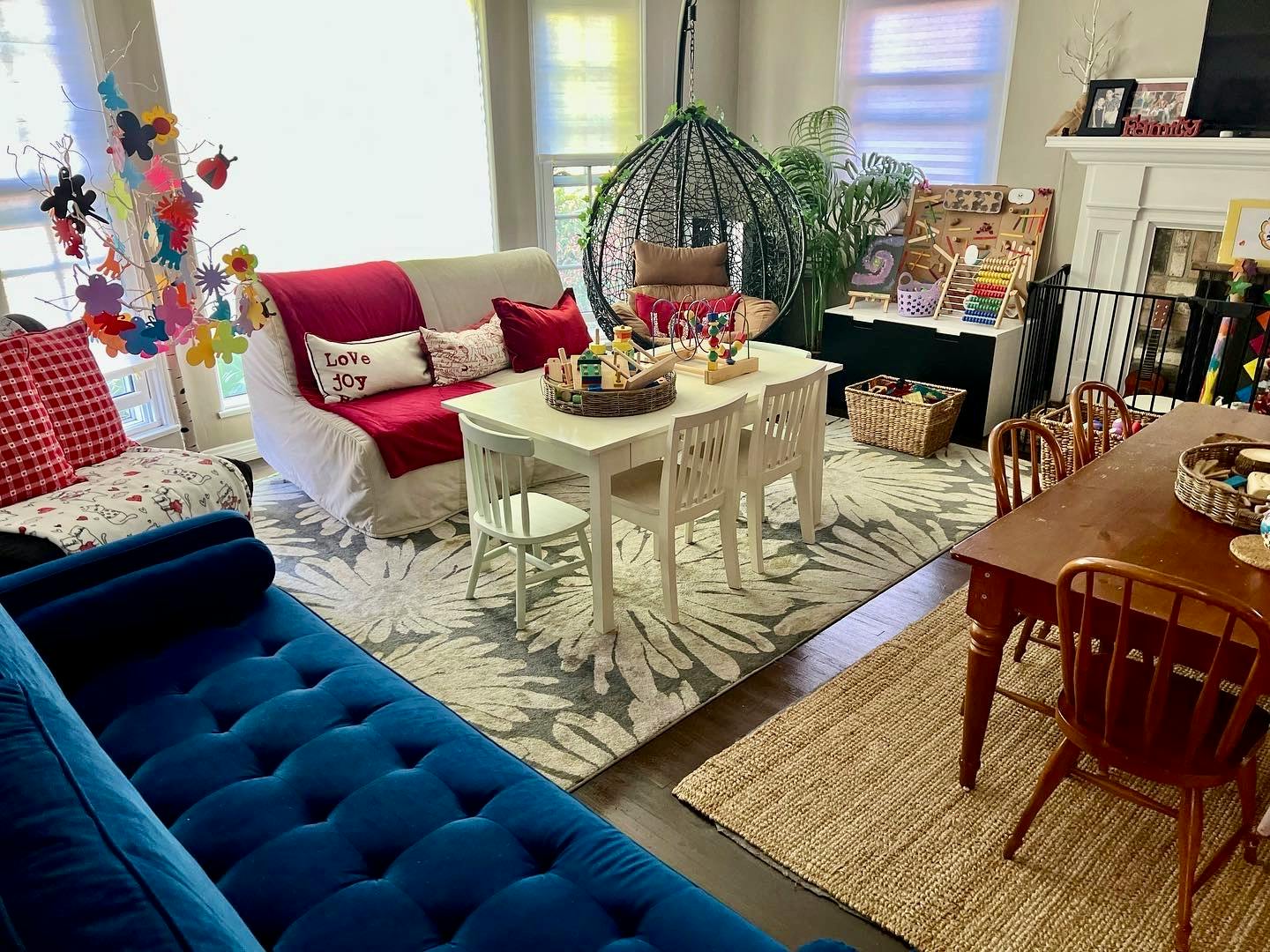 Living room with blue sofa, white sofa, white table with chairs, and wooden dining table