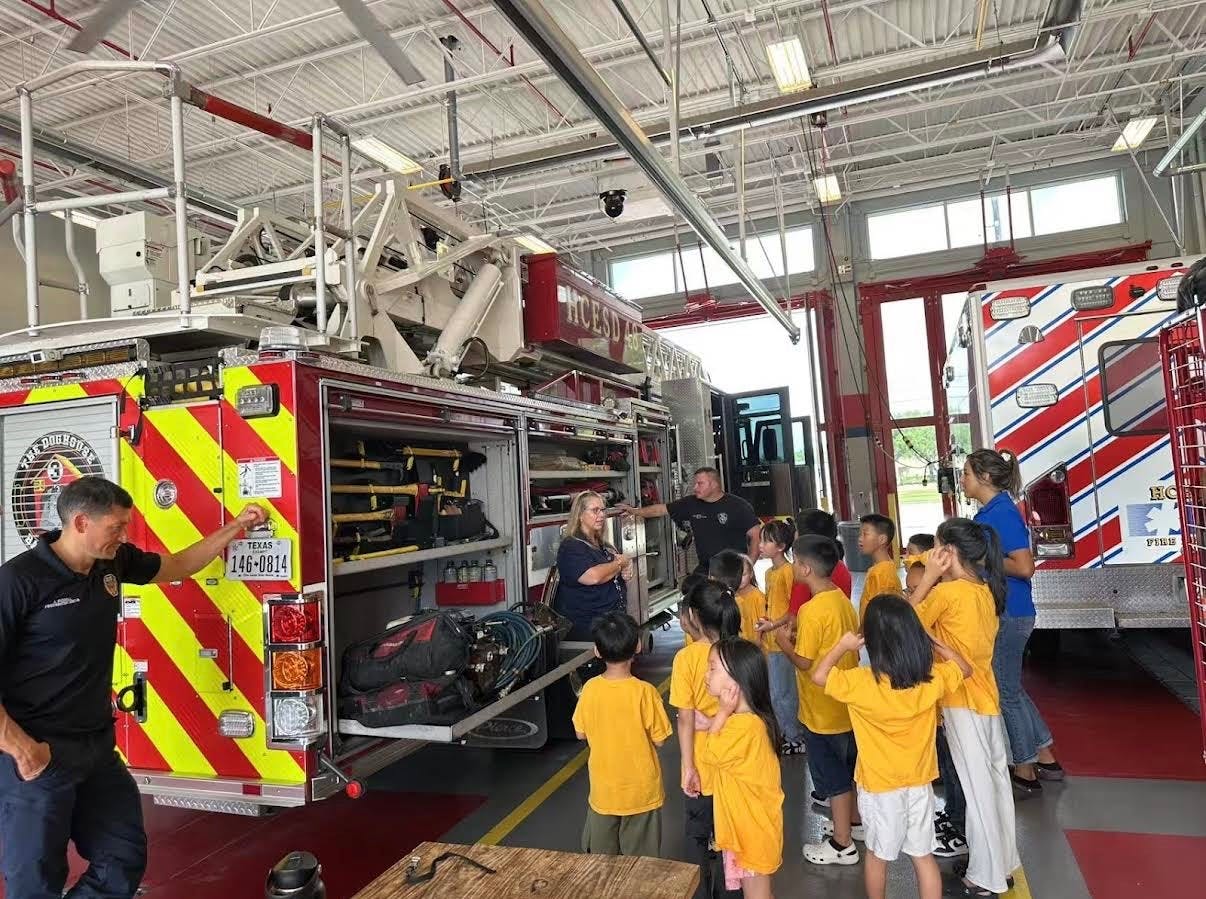 Firefighters showing tools on a fire truck to a group of children