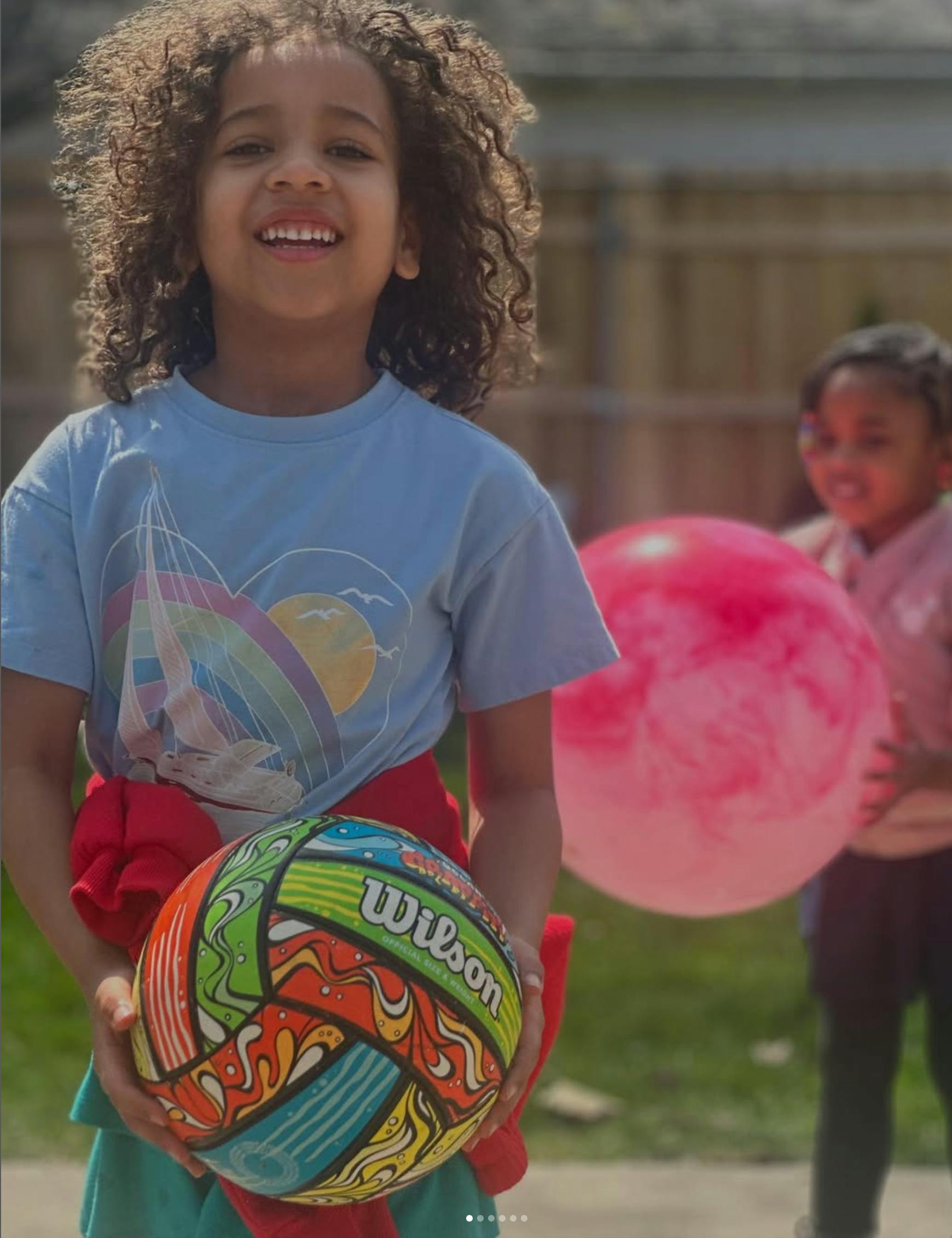Two children playing with colorful balls outdoors