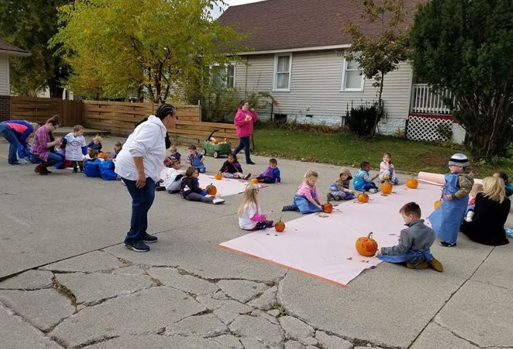 Adults and children sitting on blankets with pumpkins outdoors