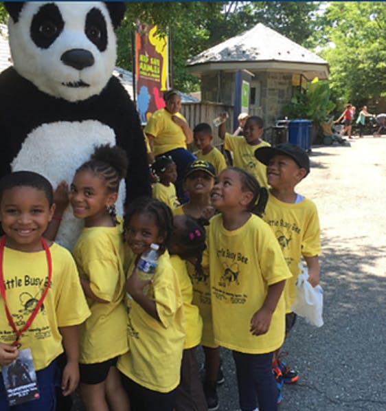 Children in yellow shirts with a person in a panda costume