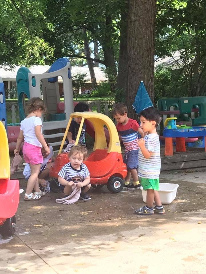 Children playing outdoors with toy cars and playground equipment