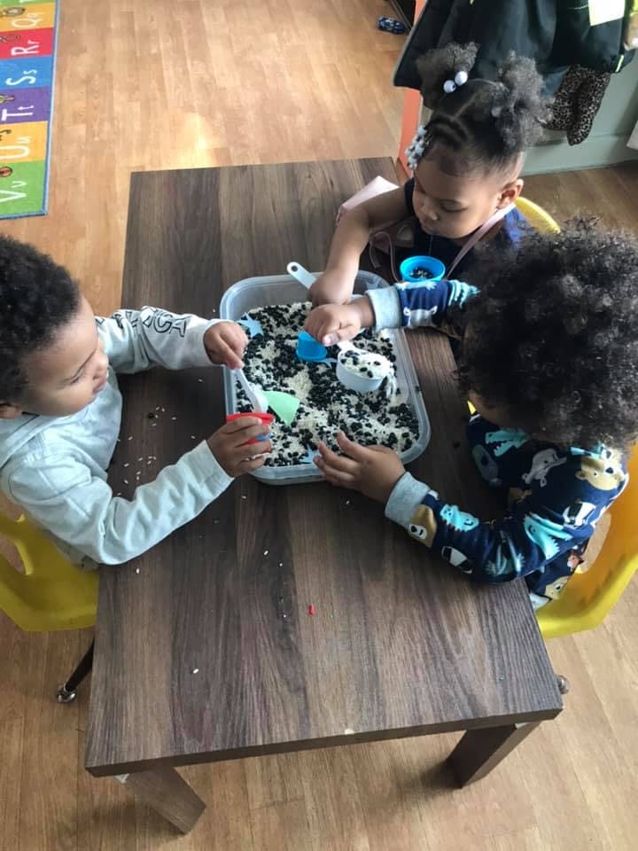 Three children playing with sensory bin at a table