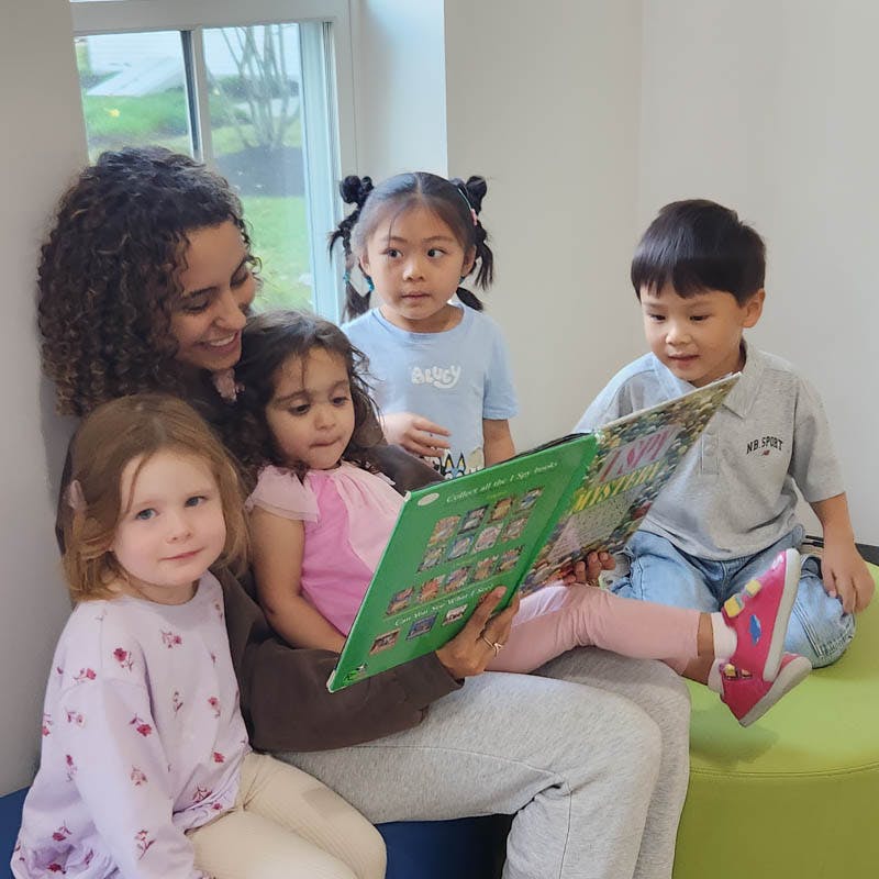 Adult reading a book to four children