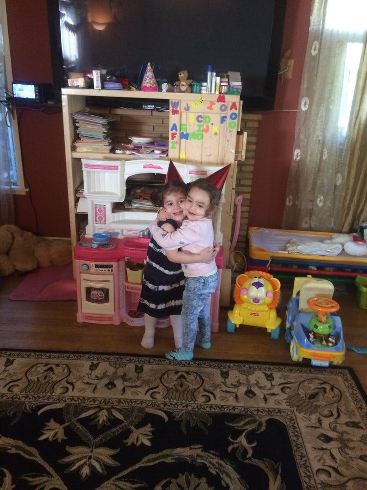 Two children wearing party hats hugging in a room with toys