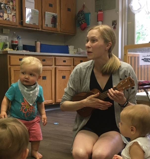 Person playing ukulele for children in a classroom