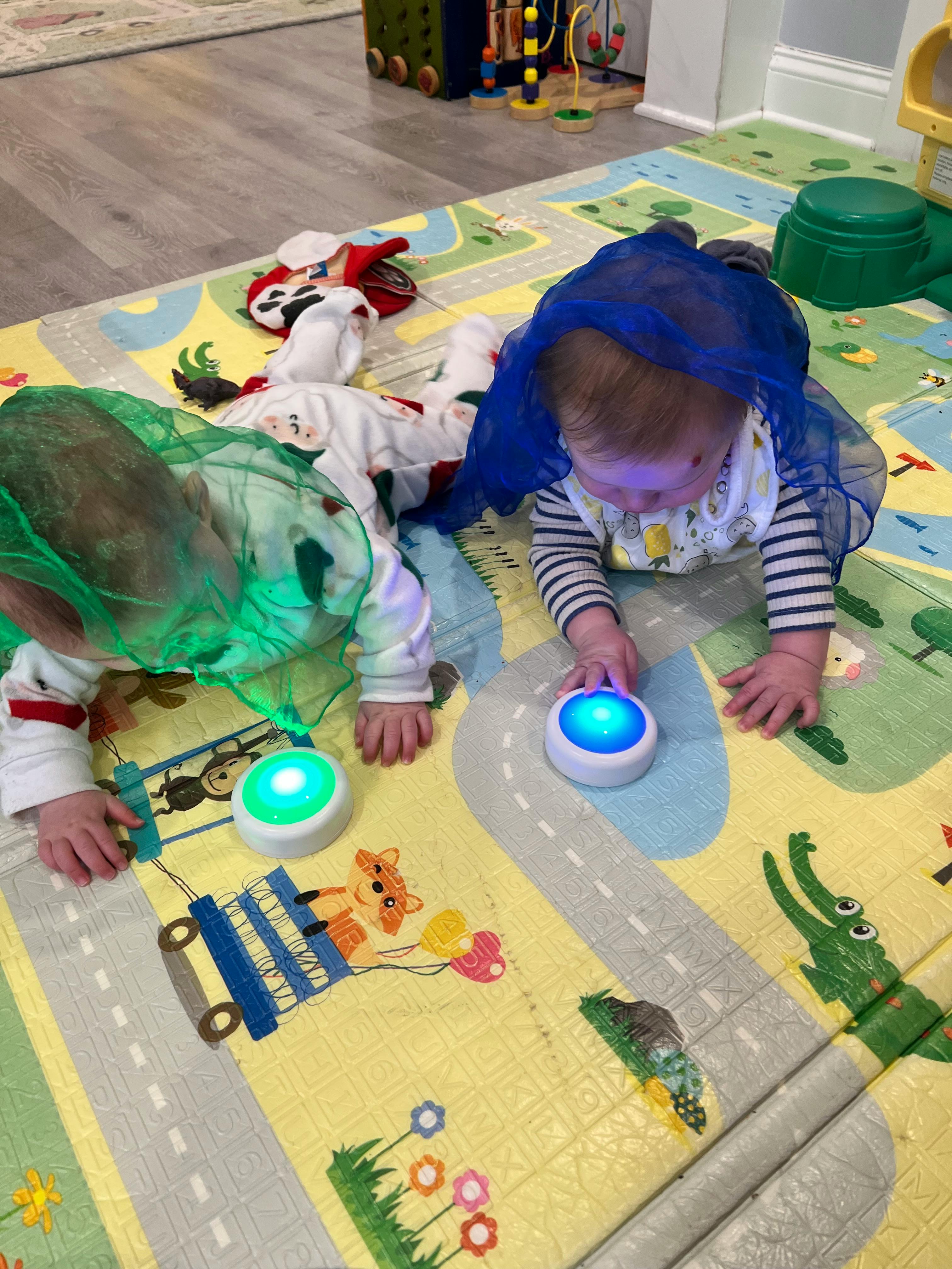Two children crawling on a playmat with light-up toys