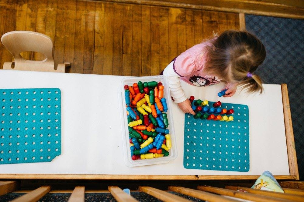Child playing with colorful pegs on a pegboard