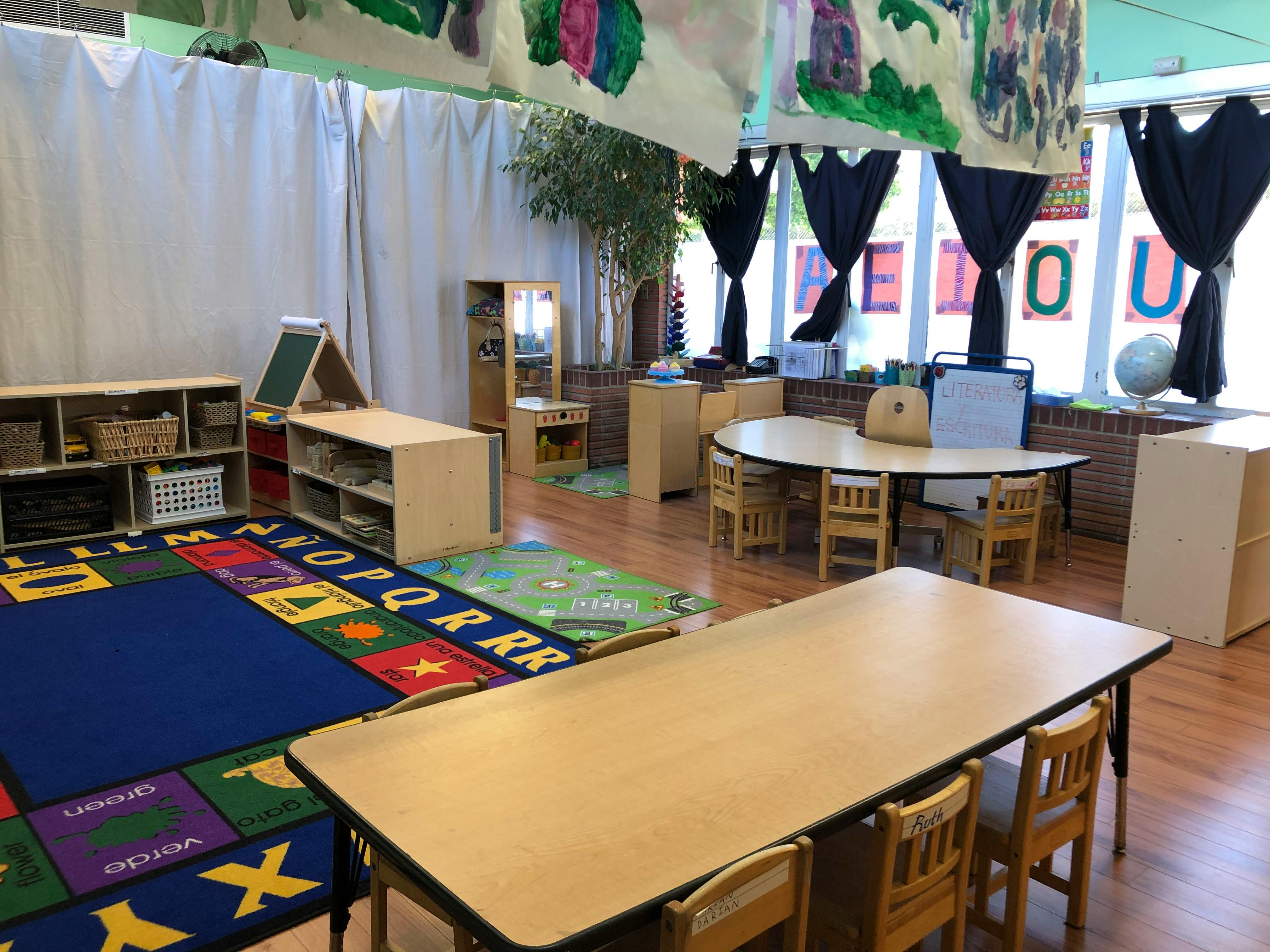 Classroom with tables, chairs, and an alphabet rug