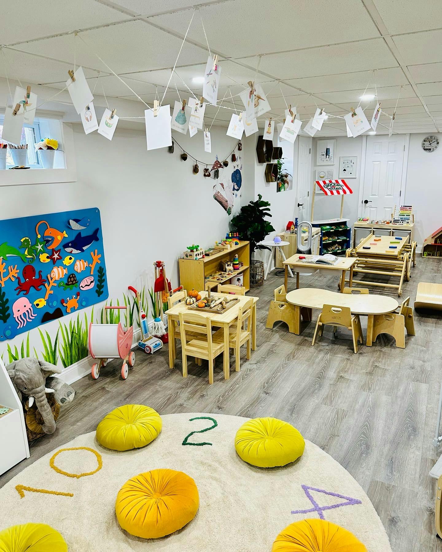 Classroom with small tables, chairs, and a rug with yellow cushions
