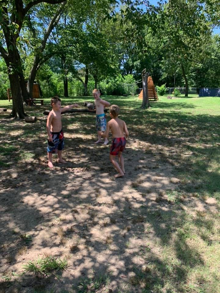 Three children playing outdoors in swim trunks