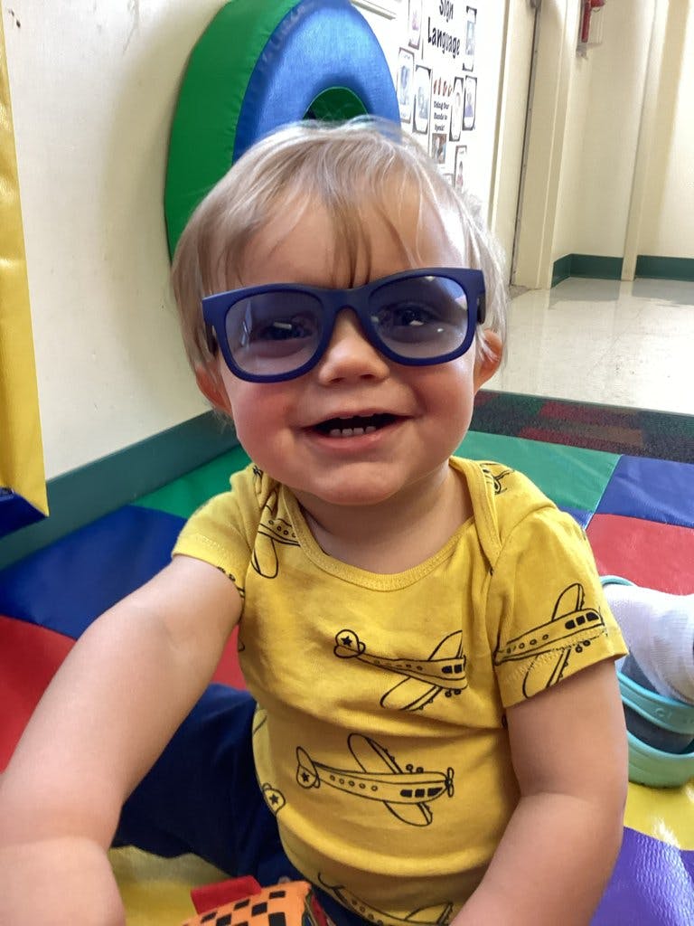 Child wearing sunglasses and a yellow shirt with airplanes
