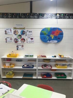 Classroom with shelves of learning materials and a world map on the wall