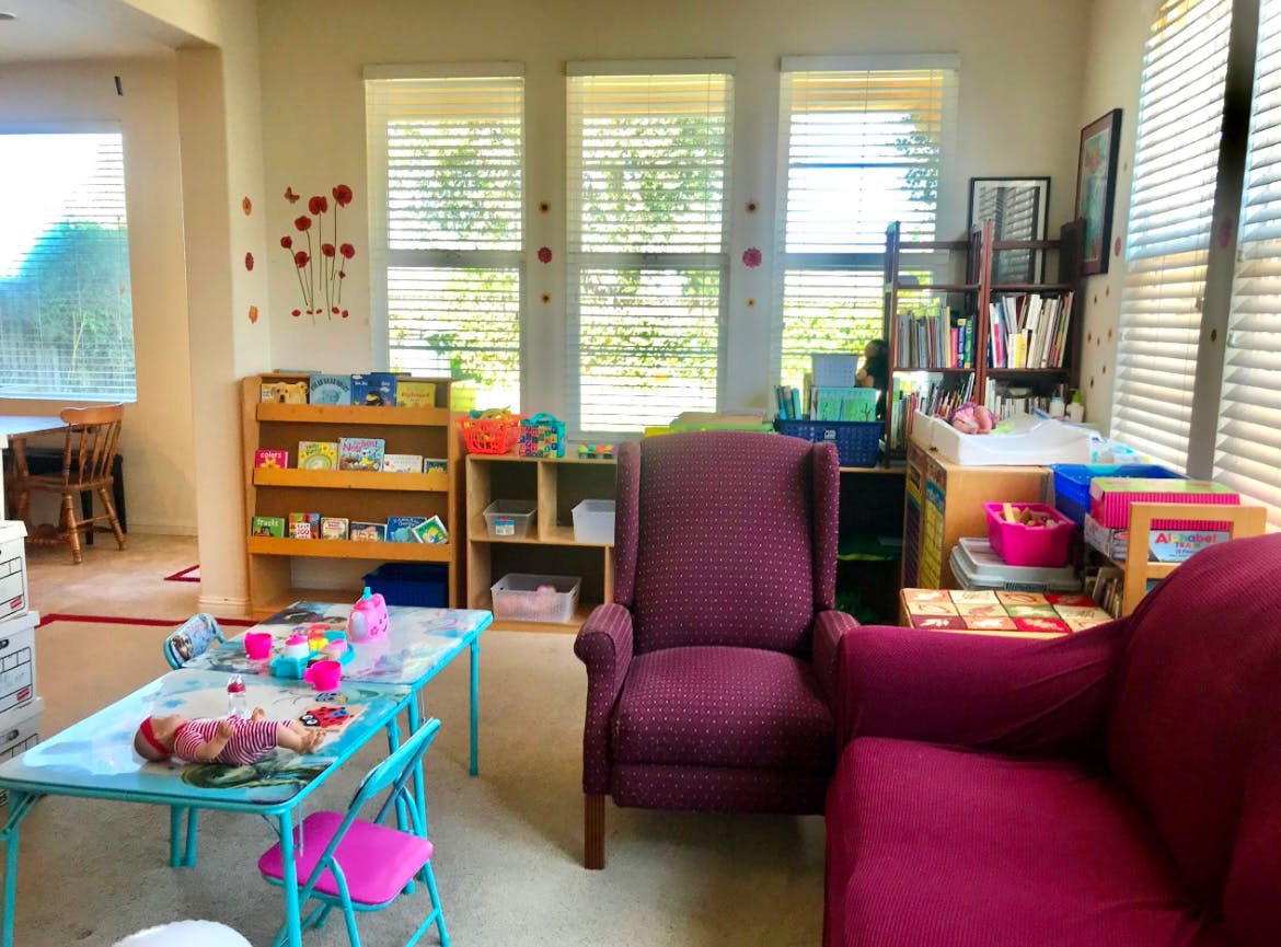 A room with a small table and chairs, bookshelves, and two armchairs