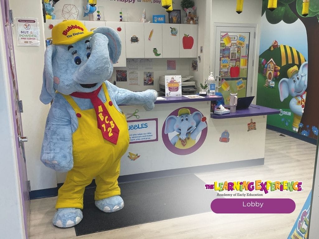 Elephant mascot in yellow overalls and red tie standing in a lobby